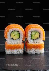 Fresh salmon sushi rolls with avocado on black slate