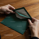 Person opening a green envelope on wooden table