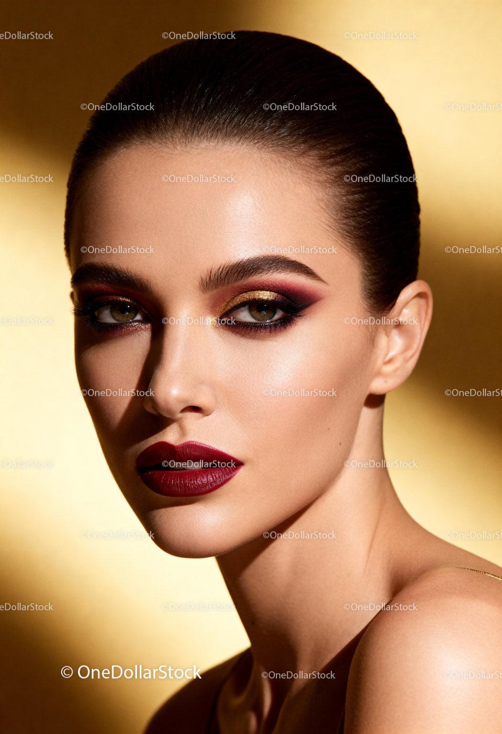Elegant woman with bold makeup on golden background