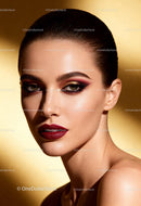 Elegant woman with bold makeup on golden background