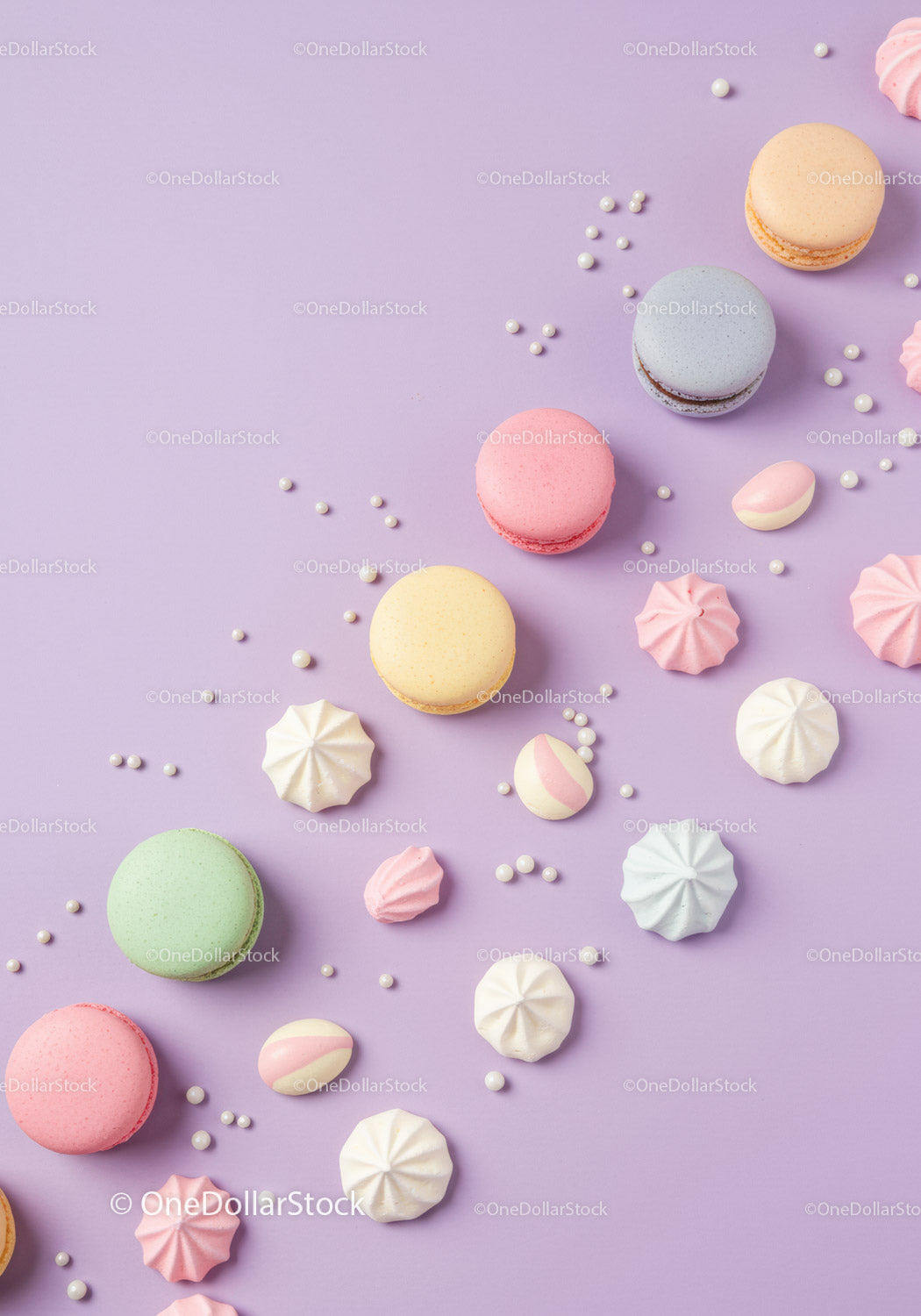 Assorted pastel macarons and meringues on lavender background