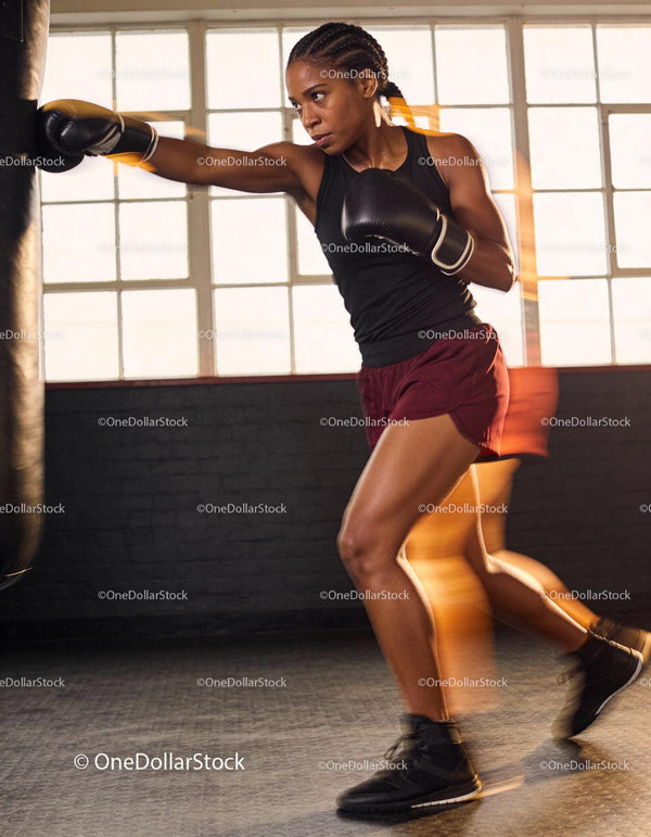 Focused woman training boxing punches indoors