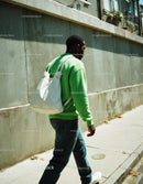 Young Man in Green Sweater Walking Through Urban Street Scene