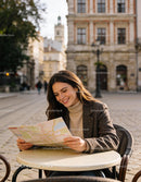Smiling Woman Exploring City Map at Outdoor Café