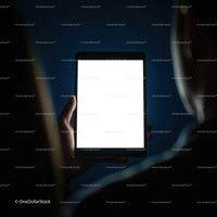 Person Holding Bright Digital Tablet in Dark Room
