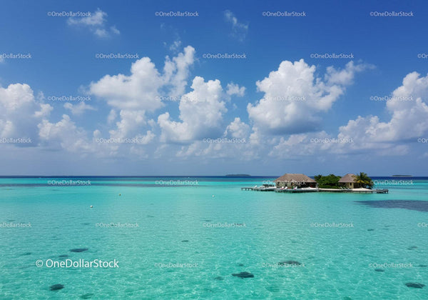 Tropical Overwater Bungalows Beneath Blue Sky and Fluffy Clouds