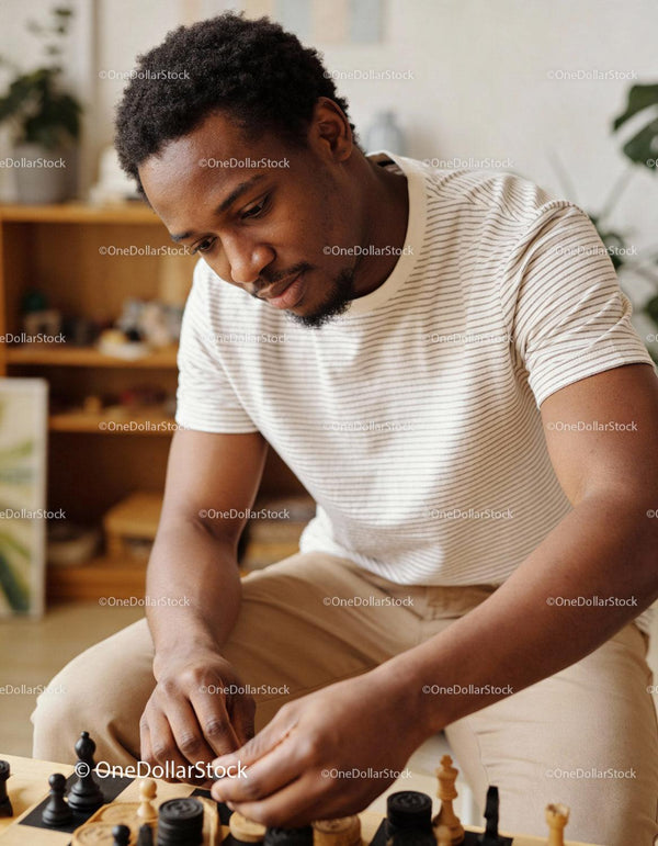 Focused young man playing chess in cozy living room