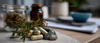 Herbal Medicine Capsules and Organic Herbs on rustic surface