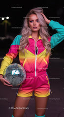 Vibrant Party Girl in Colorful Tracksuit Holding Disco Ball at Night