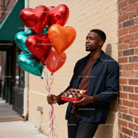 Man holding heart balloons and chocolates outdoors