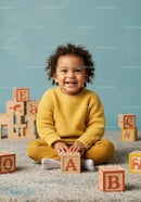 Happy toddler playing with wooden alphabet blocks indoors