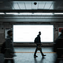 Commuters walking past a blank subway advertisement