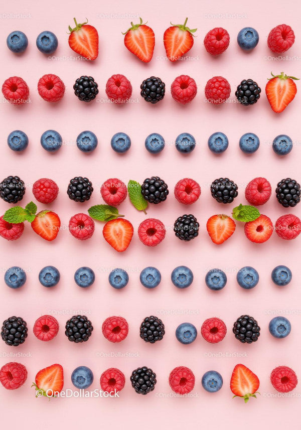 Colorful fresh berries and mint leaves on pink background