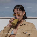 Stylish Woman Drinking Smoothie Outdoors Under Blue Sky