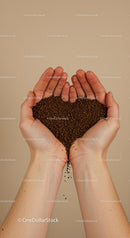 Hands shaping coffee granules into heart symbol