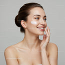 Beautiful Young Woman Applying Skincare Cream with a Bright Smile