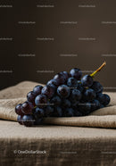 Fresh dark grapes resting on rustic linen cloth
