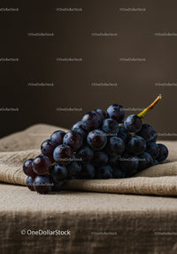 Fresh dark grapes resting on rustic linen cloth