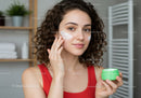 Young Woman Applying Face Moisturizer in Indoor Bathroom
