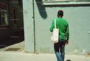 Man Walking in Green Sweater and Jeans Along City Street