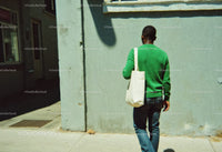 Man Walking in Green Sweater and Jeans Along City Street