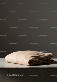 Beige Silk Shirt Folded on Grey Surface with Minimalist Style