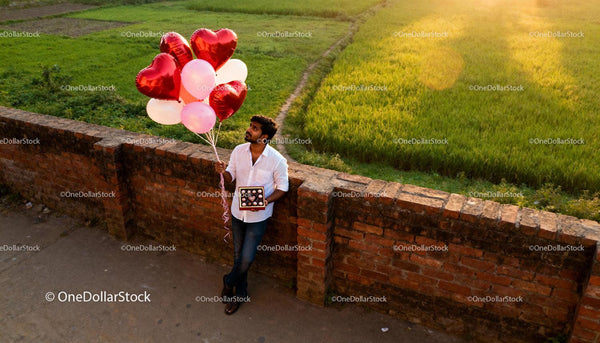 Man Holding Heart Balloons and Chocolates in Sunset Light