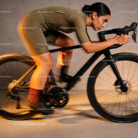 Focused female cyclist training indoors on black road bike