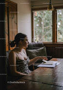 Young Woman Sitting at Desk with Notebook in Cozy Home Office