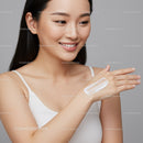 Young Woman Applying Skincare Cream with a Bright Smile