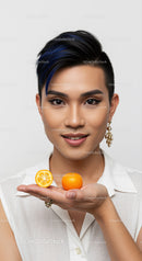 Young Woman with Short Hair Holding Oranges and Smiling