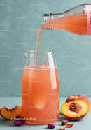 Refreshing peach juice poured into glass pitcher with ice