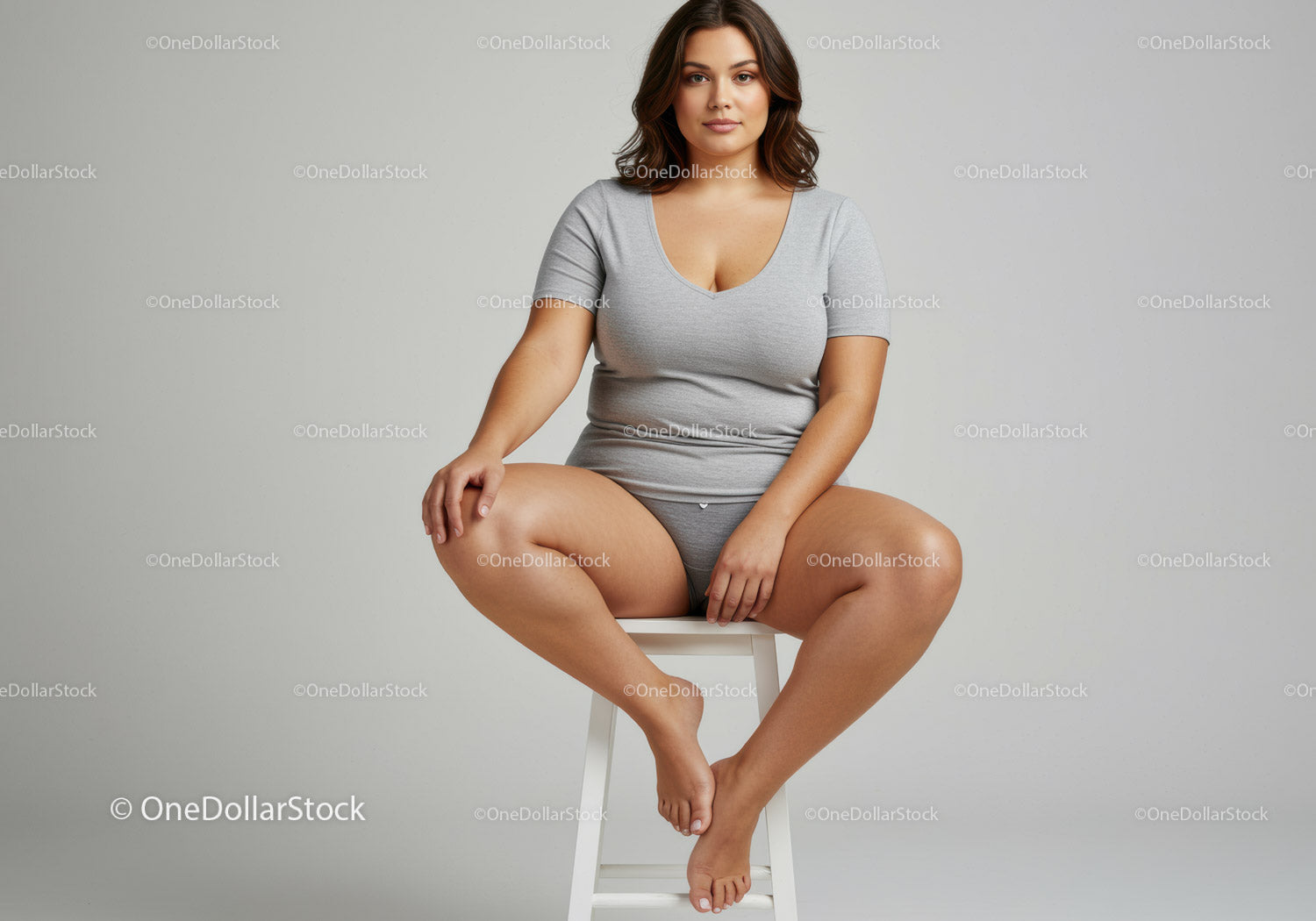 Confident Woman Sitting Cross-Legged on Stool in Casual Grey T-Shirt