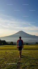 Young man Hiking Toward Mountain Volcano in Scenic Countryside