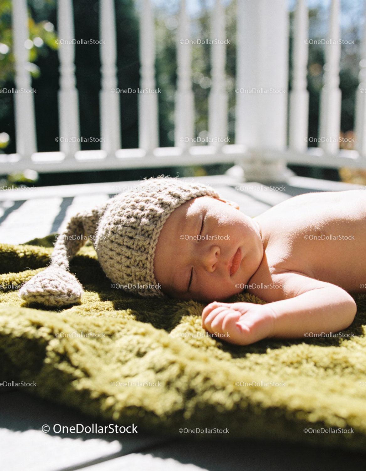 Newborn baby peacefully sleeping on green blanket outdoors