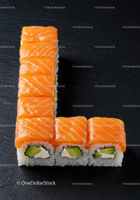 Fresh salmon sushi rolls arranged in L shape on black slate