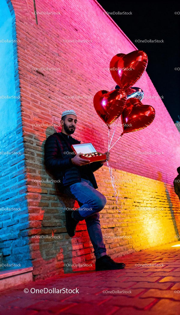 Man with Heart Balloons and Chocolates on Colorful Street
