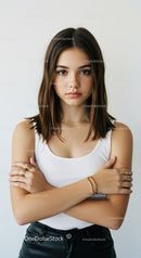 Young Woman with Confident Expression Wearing White Tank Top and Gold Jewelry