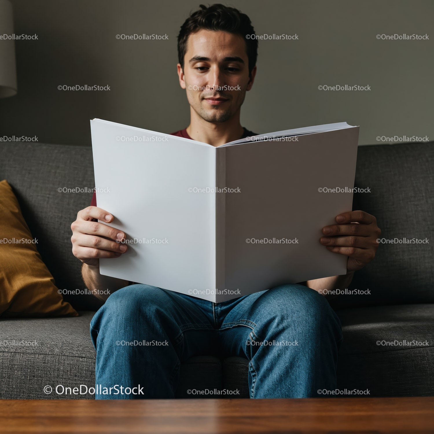 Man reading large book while sitting on couch