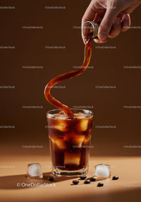 Pouring Iced Coffee Amid Coffee Beans and Ice Cubes