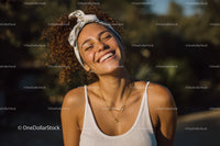 Joyful Woman with Curly Hair and Headband Smiling Outdoors