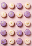 Purple and beige macarons with gold flakes on pink background