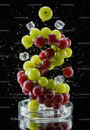 Red and green grapes splashing with ice cubes on black