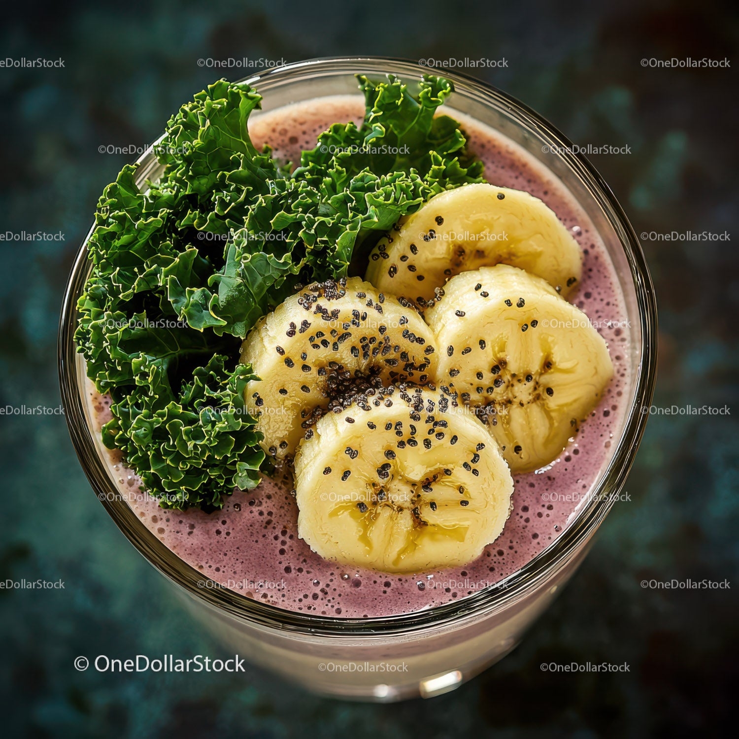 Plasterki banana i liście jarmużu w szklance soczystego smoothie jagodowego