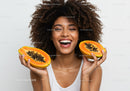 Vibrant Female Holding Fresh Papaya Halves in Bright Studio