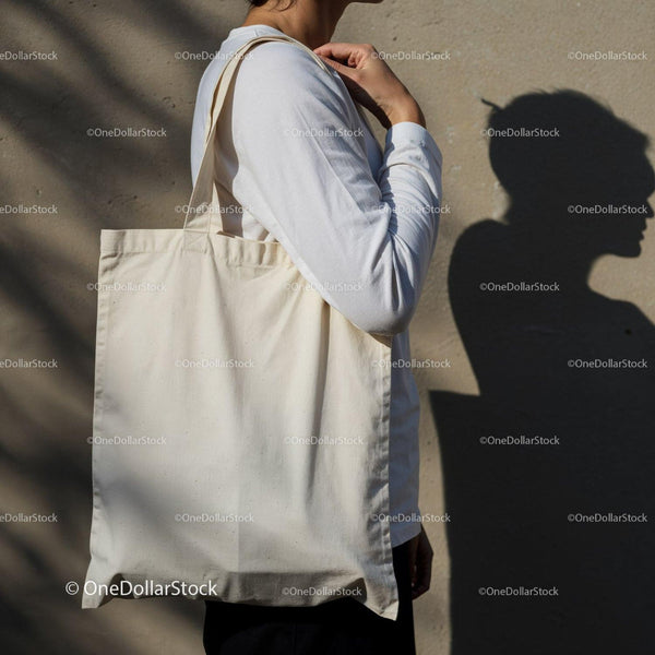 Person Carrying Plain Cotton Tote Bag Against Wall JPG Mockup Image