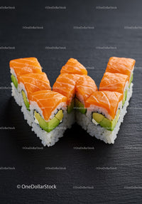 Fresh salmon sushi rolls with avocado on black slate