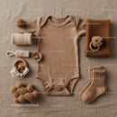Neutral toned baby clothing and accessories flat lay