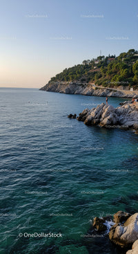 Scenic Rocky Coastline with Green Hills and Calm Blue Sea