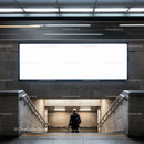 Man walking down subway stairs under blank billboard